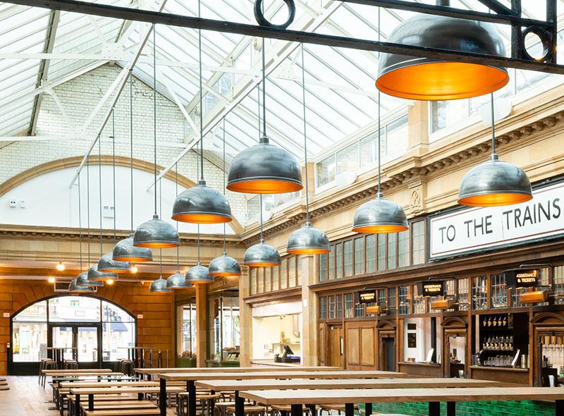 Custom industrial pendant lighting fixtures suspended above the dining area at Industville Market Hall